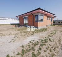 A family house in Veľký Lapáš with an unfinished facade, surrounded by a grassy plot.