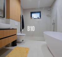 A bathroom in a family house with a bathtub, toilet, and sink, with light tiles.