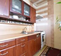 A kitchen in a 3-room apartment with cabinets featuring a wood decor and a collection of spices.