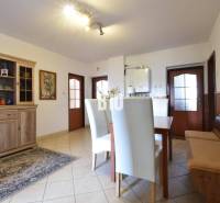 Dining area in a family house with a wooden sideboard and white chairs.