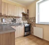A kitchen in a family house with wooden cabinets and a tile mosaic on the wall.