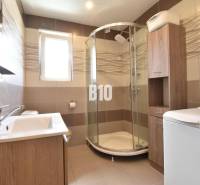 Bathroom with a sink, shower, and washing machine in a family house.