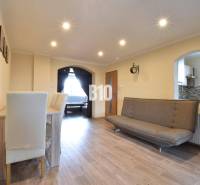 Living room with a sofa, dining table, and kitchen passage in a family house.