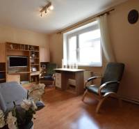 Living room with wooden furniture, a sofa, and flowers in a family house.