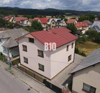 A family house in Bytča with a red roof, surrounded by other houses and nature.