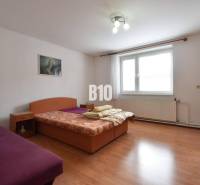 Bedroom with wooden floor, bed, and sofa in a family house.