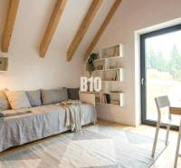 A bright room in a cabin with wooden beams, a couch, and a table on a floor with wooden decor.