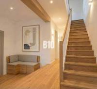 Interior of a cabin with wooden decor, stairs, bench, painting, neutral colors.
