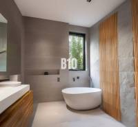A bathroom in a cabin with a freestanding bathtub, wooden details, and a large window.