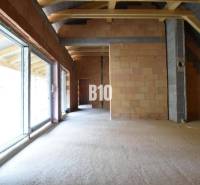 Unfinished interior of a family house with large windows and brick walls.