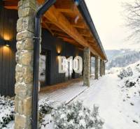 A cottage in the snowy landscape of Horná Mariková with stone pillars and wooden decor.