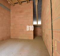 Unplastered bricks and an unfinished ceiling in a family house.