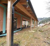 A family house under construction with a wooden shelter, flat terrain, and surrounding landscape.