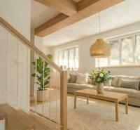 Interior of a cabin with a sofa, table, plant, and wood-patterned floor.