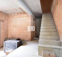 Interior of an unfinished residential house with a staircase and bricks for construction.