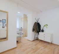 Interior of a family house with a wooden decor floor, a dresser, and a coat rack.