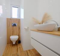 A bathroom with a sink on a dresser and a floor with a wood decor.