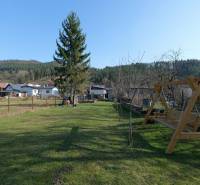 The garden of a family house on Mládeže Street in Dolný Hričov with a swing and trees.