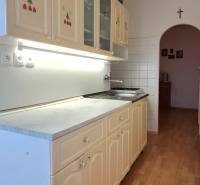 A kitchen in a 2-room apartment with a wooden decor floor and an arched transition.