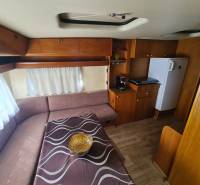 Interior of a cabin with a wood-patterned floor, a sofa, and a kitchenette.