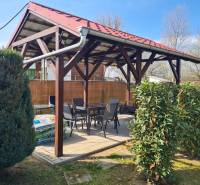 A covered terrace at the cottage in Štúrovo, surrounded by greenery and comfortable seating.
