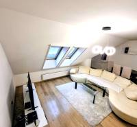 Living room in a three-room apartment with a wooden decor floor and a comfortable couch.