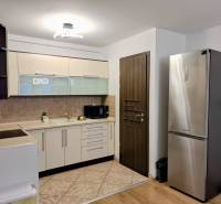 A kitchen in a 3-room apartment with white cabinets and a stainless steel refrigerator.