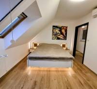 A bedroom in a three-room apartment with a wooden decor floor and art on the wall.