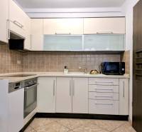 A kitchen in a 3-room apartment with tiles and appliances, cream-colored cabinet doors.