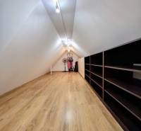 Attic room in a 3-room apartment with a wooden decor floor and shelves.