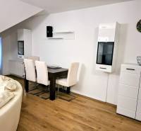 A bright living room in a three-room apartment with wooden decor flooring and light furniture.