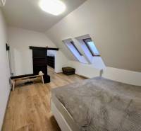 A bright bedroom with wood-patterned flooring in a three-room apartment.