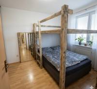 Bedroom in a 2-room apartment with a bunk bed, wooden decor flooring, and a mirror.