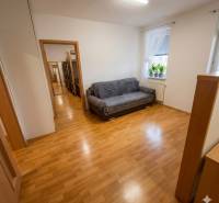 A room with a sofa bed, a window, and a floor with a wooden decor in a 2-room apartment.