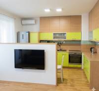 A kitchen in a 2-room apartment with wooden decor and light green furniture.