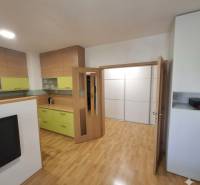 Kitchen and living room in a 2-room apartment with wood-patterned flooring.