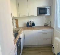 A kitchen in a 3-room apartment with white cabinets and a wood-patterned floor.