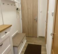 A hallway in a 3-room apartment with a coat rack, a bench, and an entrance door.