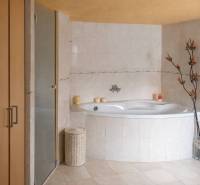 A bathroom in a family house with a corner bathtub, decorative flowers, and beige tiles.