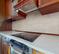 A kitchen in a 5 or more room apartment with wooden cabinets and ceramic tiles.