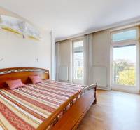 A bedroom with a bed, wooden decor flooring, and large windows in a 5 or more room apartment.