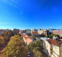 A view of Bratislava from Lazaretská Street, surrounded by greenery and rooftops of buildings.
