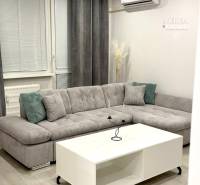 Living room in a two-room apartment with a gray sofa and a white table.