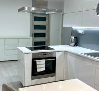 A kitchen in a 2-room apartment with white cabinets and built-in appliances.