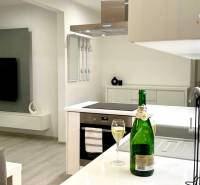 A stylish kitchen with an island, a cooktop, and a glass of wine in a two-room apartment.