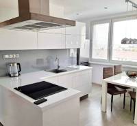 A kitchen in a 2-room apartment with white cabinets, a dining table, and a wooden decor floor.