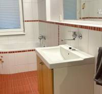 Bathroom with a bathtub, sink, and mirror in a 2-room apartment. White tiles with a decor.