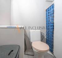 A bathroom in a 3-room apartment with a washing machine, toilet, and blue curtain.