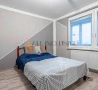 A bedroom with a bed, a table, and a wooden decor floor in a 3-room apartment.