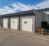 Warehouses and halls in Žilina with sectional garage doors and pallets next to the building.